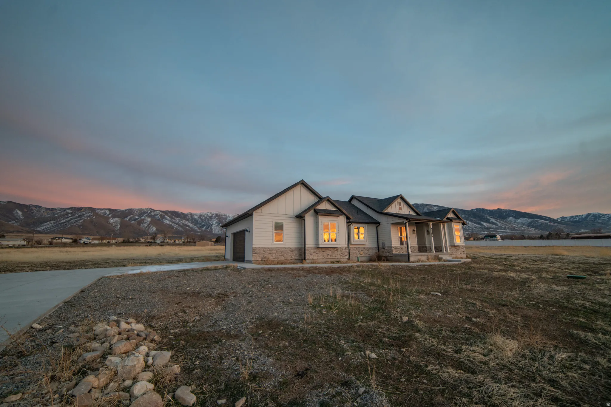 Modern inspired farmhouse featuring a mountain view, stone siding, board and batten siding, covered porch, and concrete driveway