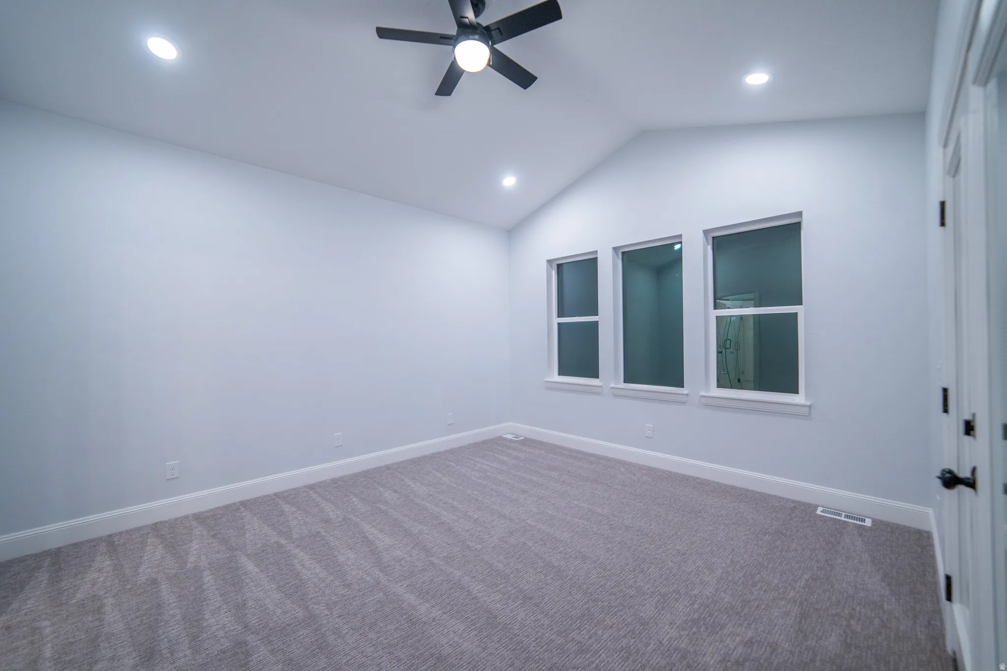 Carpeted spare room featuring vaulted ceiling, a ceiling fan, and recessed lighting