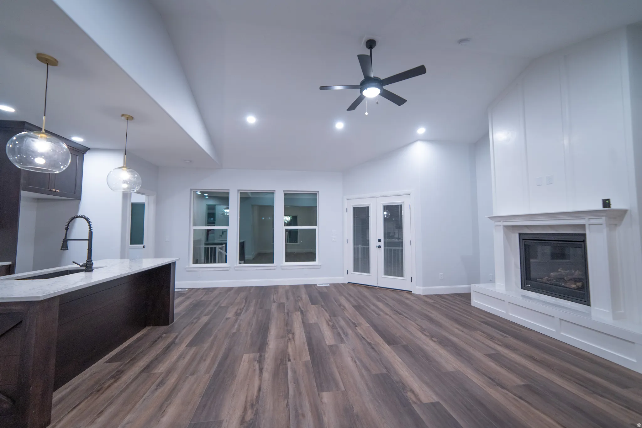 Unfurnished living room featuring lofted ceiling, a glass covered fireplace, ceiling fan, dark wood-type flooring, and recessed lighting