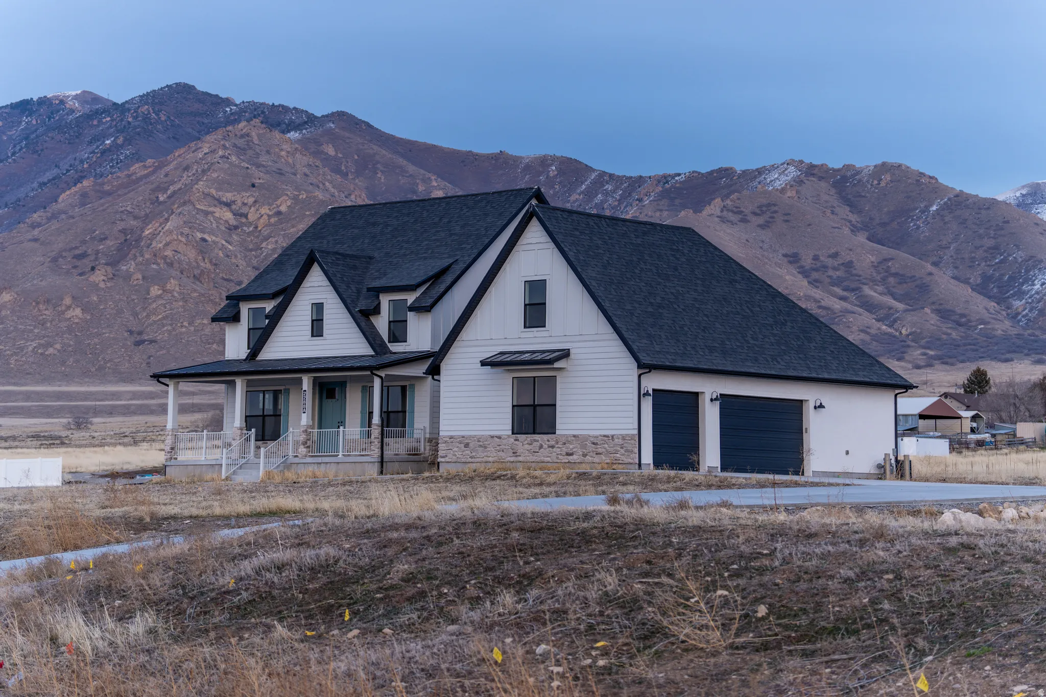 Modern inspired farmhouse featuring a mountain view, covered porch, a garage, a shingled roof, and driveway