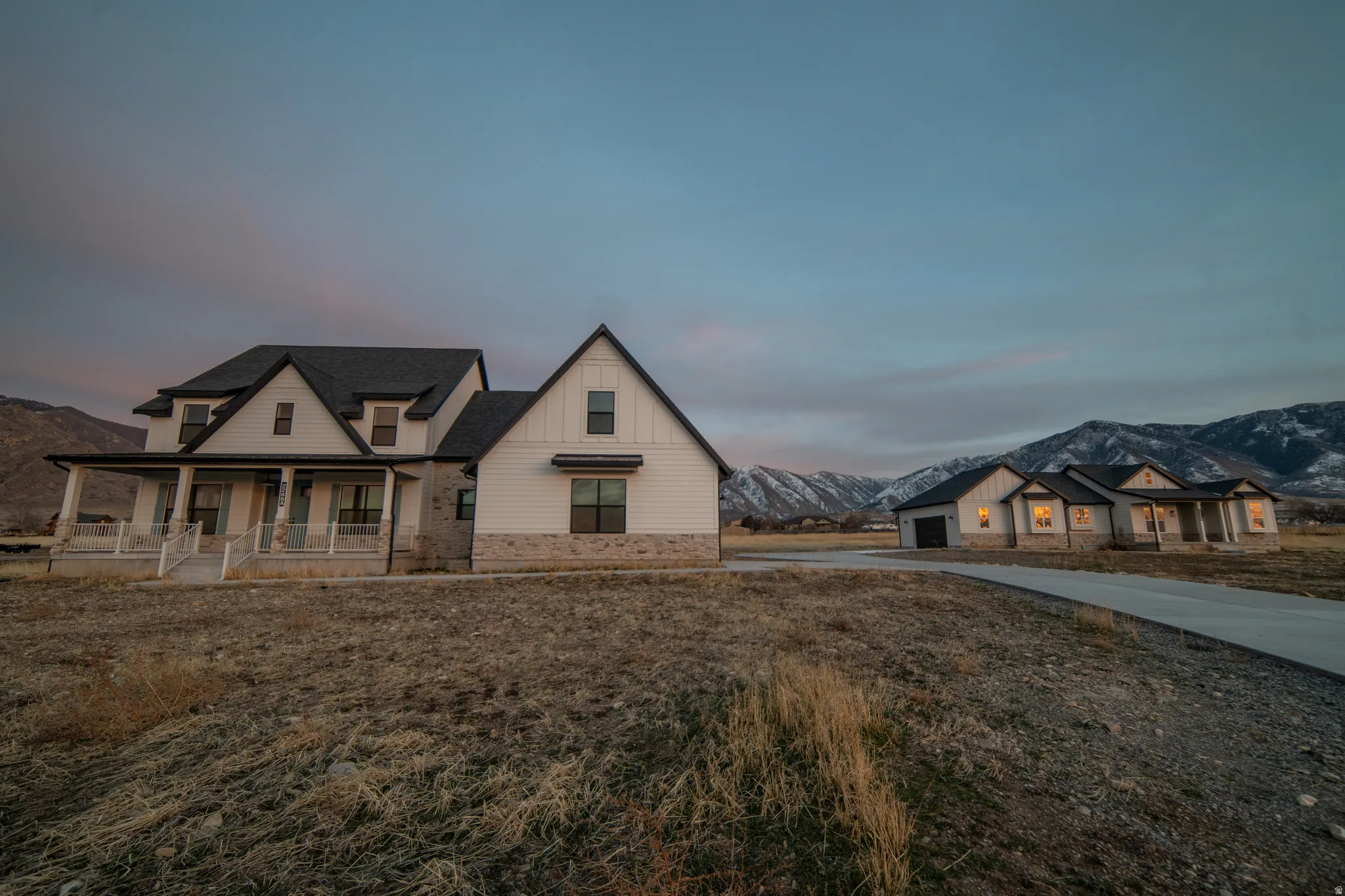 Modern farmhouse with a mountain view, covered porch, concrete driveway, and board and batten siding