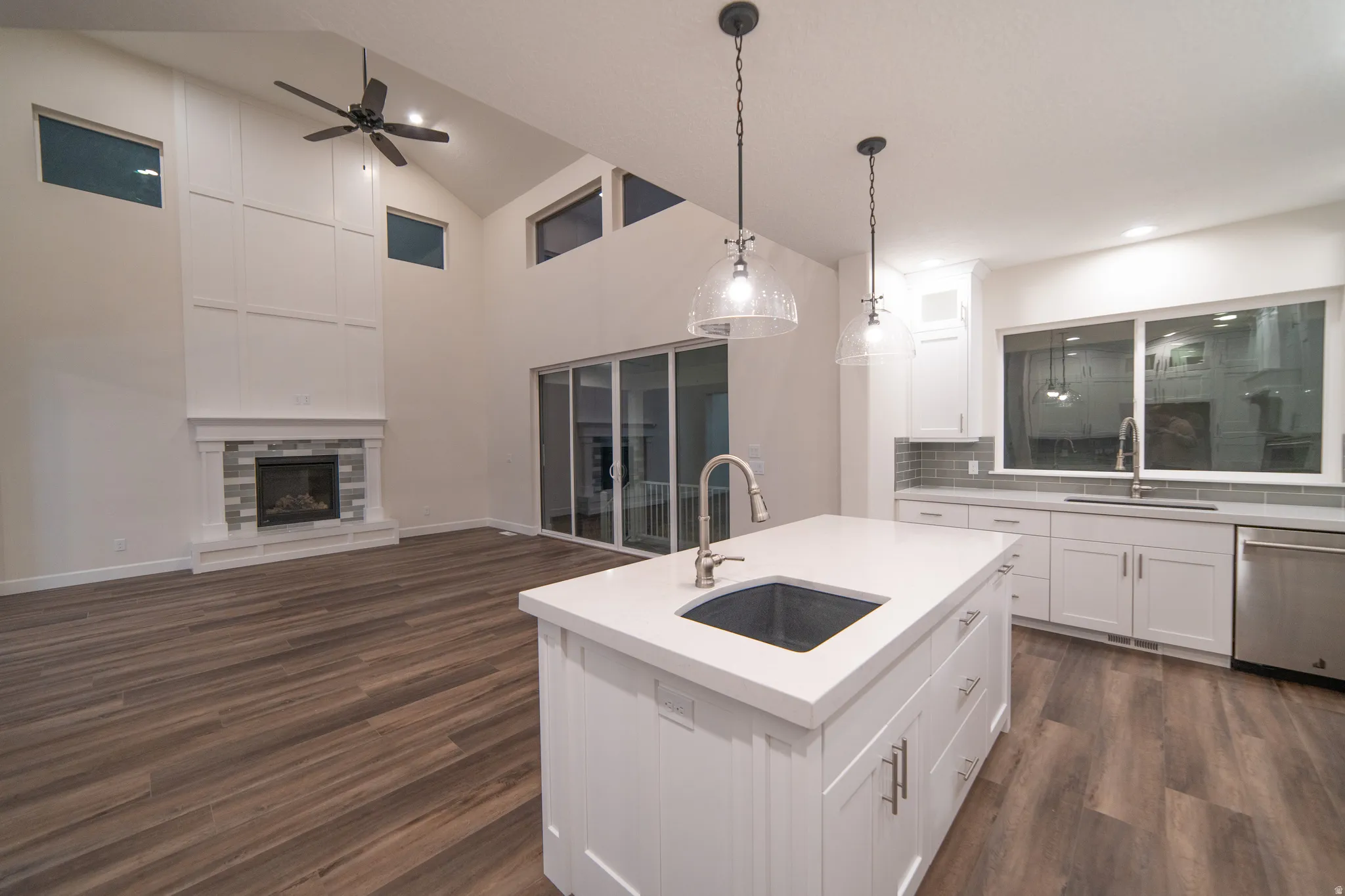 Kitchen with an island with sink, open floor plan, pendant lighting, dishwasher, and white cabinetry