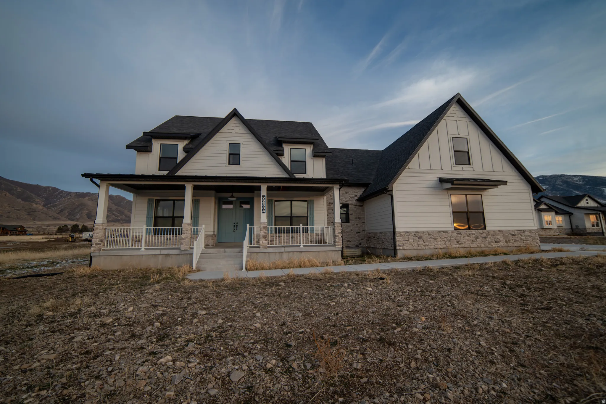 Modern farmhouse featuring covered porch, a mountain view, board and batten siding, a shingled roof, and stone siding