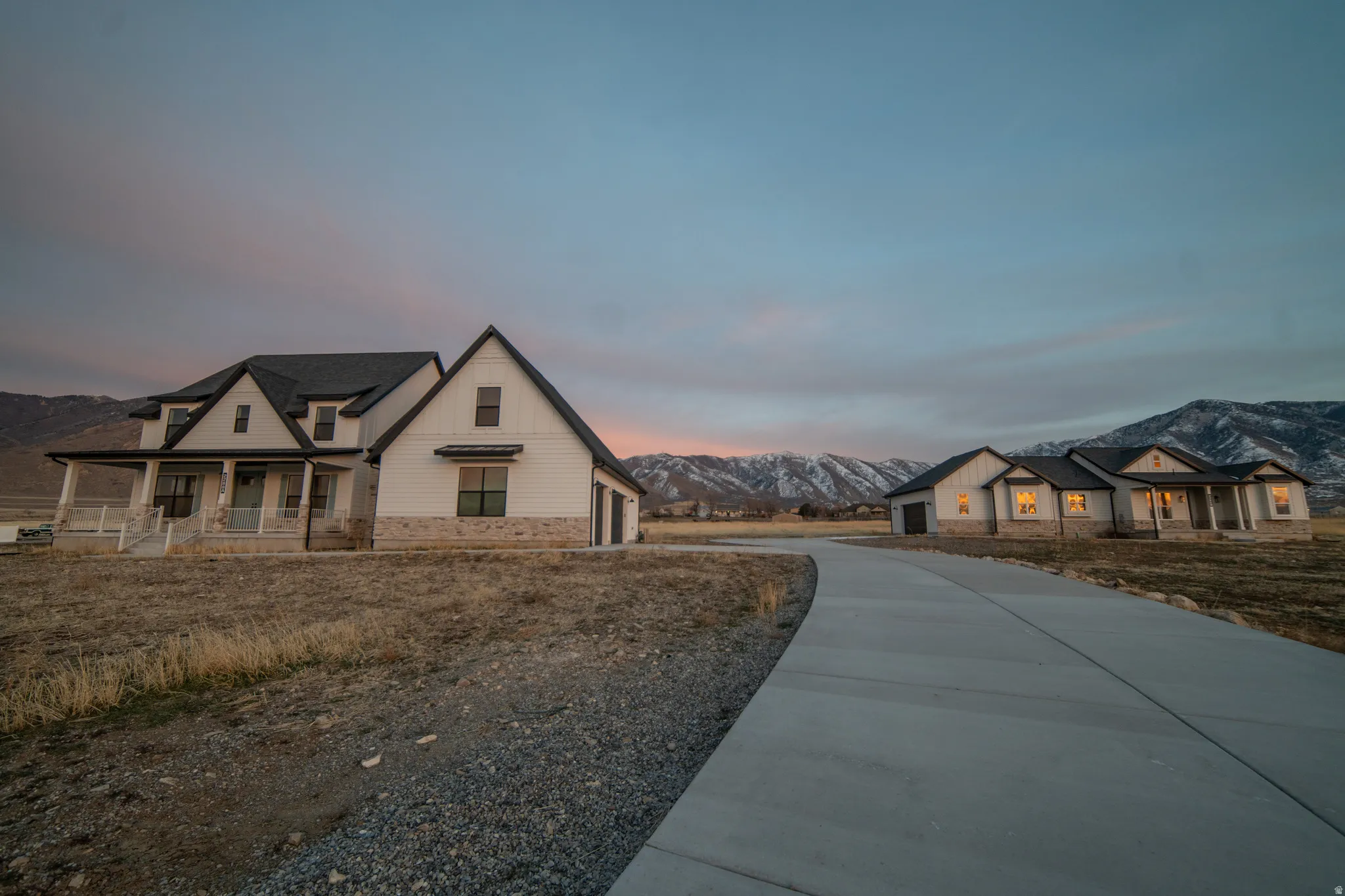 Modern inspired farmhouse featuring a mountain view, covered porch, concrete driveway, a garage, and stone siding