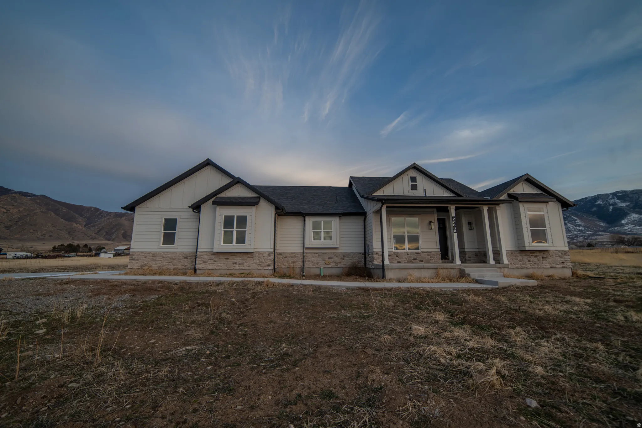 Modern inspired farmhouse featuring a mountain view, covered porch, board and batten siding, and stone siding