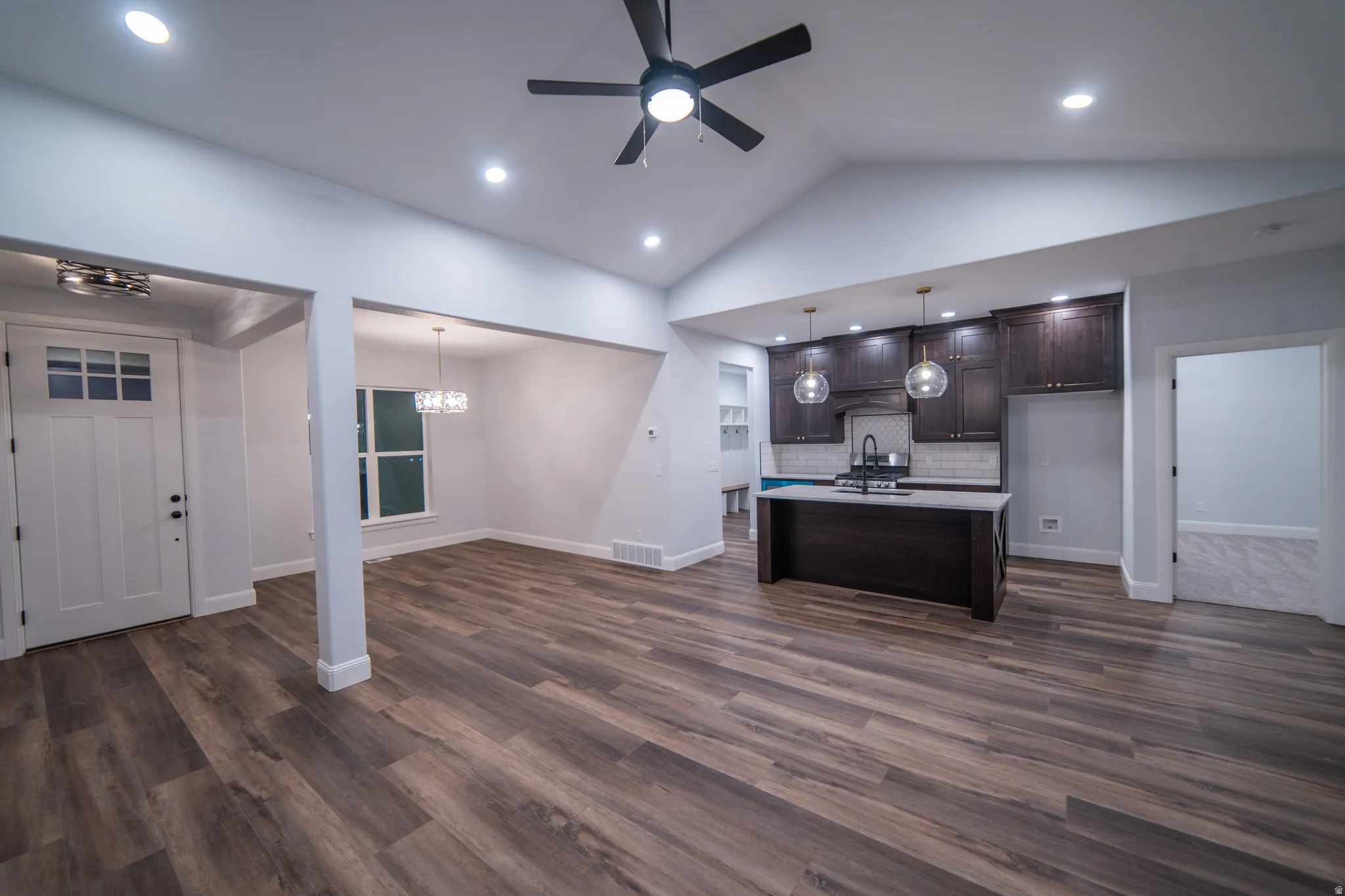 Kitchen with dark brown cabinetry, open floor plan, light countertops, recessed lighting, and hanging light fixtures