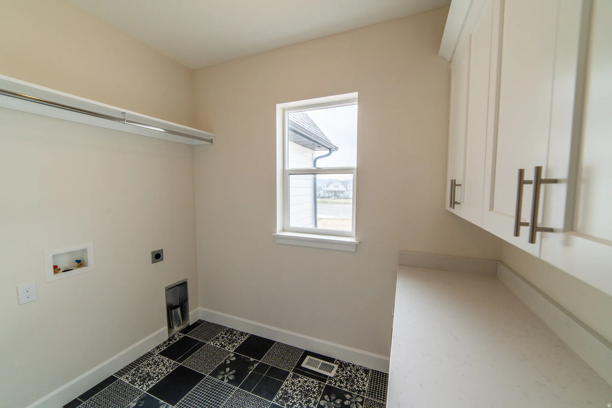 Laundry area with hookup for an electric dryer, dark tile patterned flooring, and hookup for a washing machine