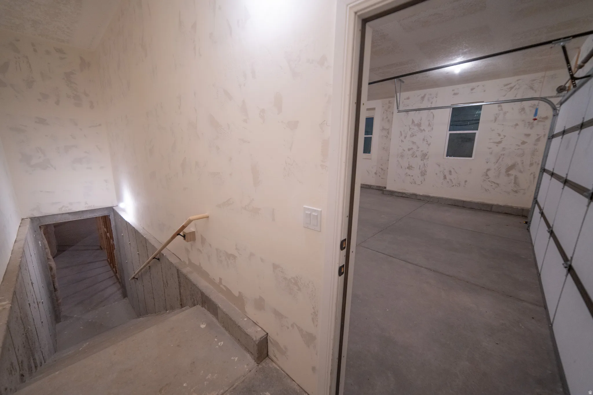 Stairs featuring unfinished concrete flooring and wallpapered walls