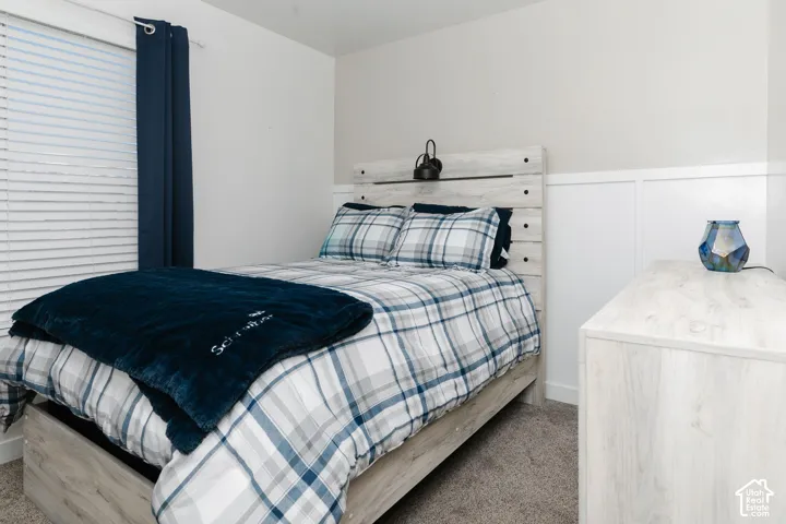 Bedroom 2 featuring light carpet, a wainscoted wall, and a decorative wall