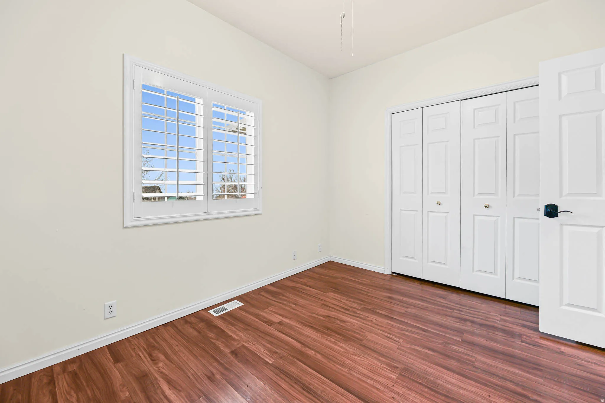Unfurnished bedroom with dark wood-style flooring and a closet