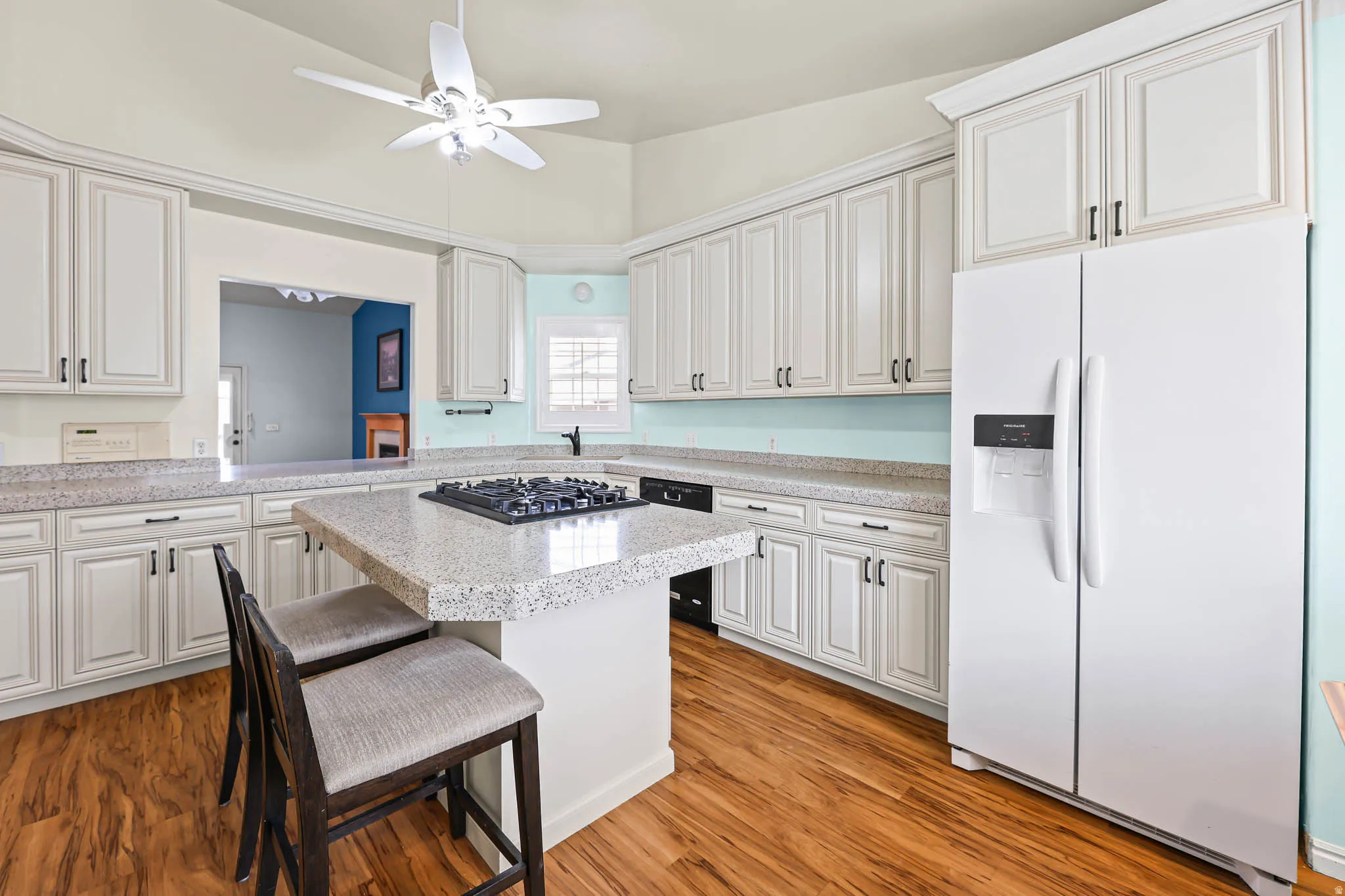 Kitchen featuring white fridge with ice dispenser, light countertops, a kitchen breakfast bar, and light wood-style flooring