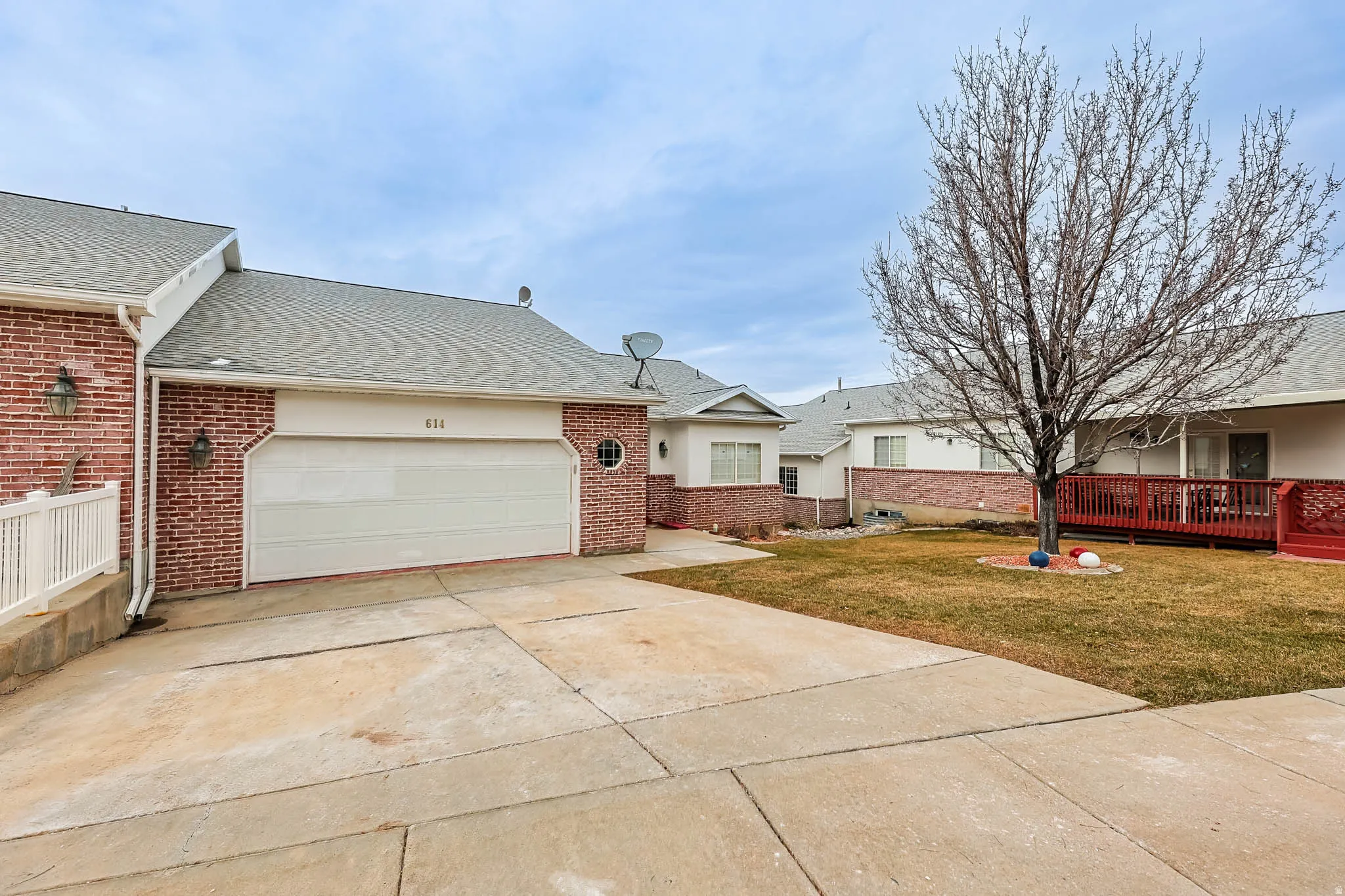 View of front of property featuring a front lawn, a shingled roof, driveway, a garage, and brick siding