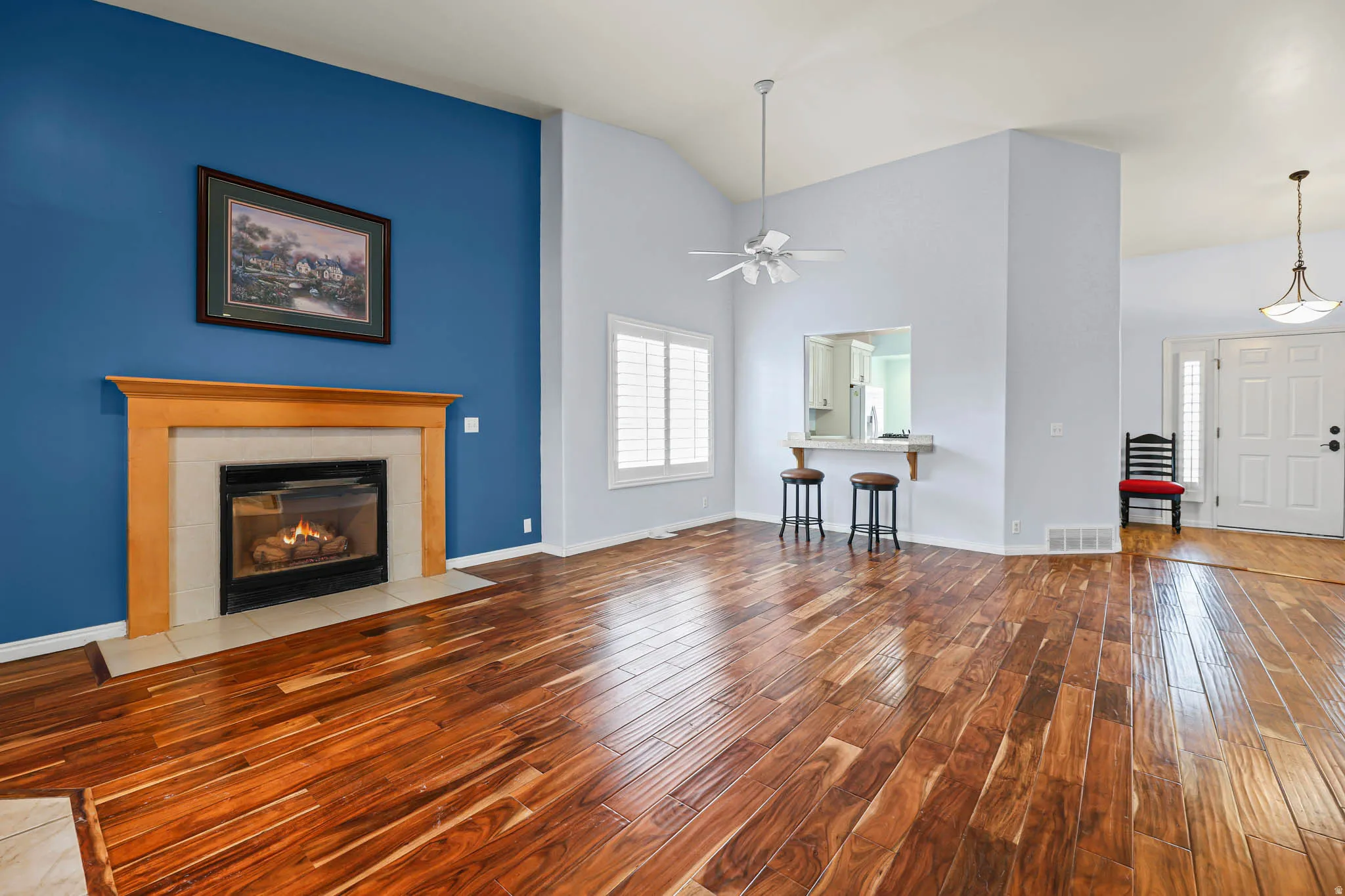 Unfurnished living room featuring light wood-style floors, high vaulted ceiling, a fireplace, and ceiling fan