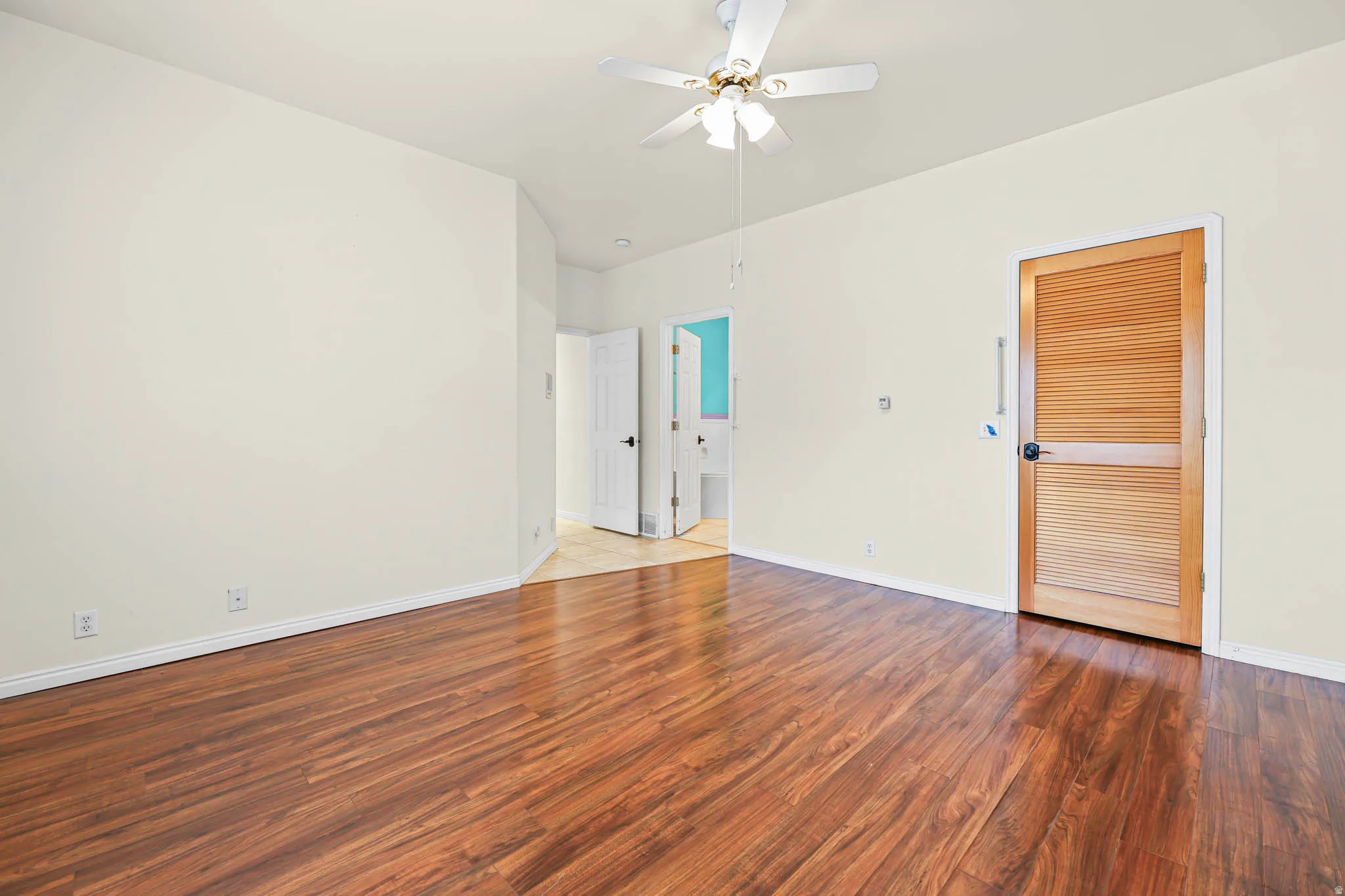 Unfurnished bedroom featuring wood finished floors, a ceiling fan, and ensuite bathroom
