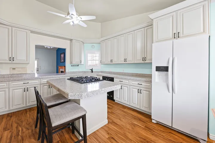 Kitchen featuring white fridge with ice dispenser, light countertops, a kitchen breakfast bar, and light wood-style flooring