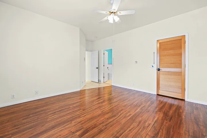 Unfurnished bedroom featuring wood finished floors, a ceiling fan, and ensuite bathroom