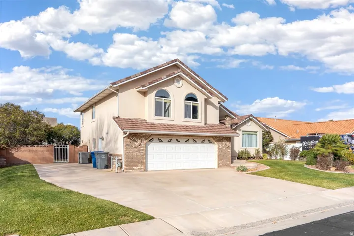 View of front of property with an attached garage, concrete driveway, a gate, stucco siding, and brick siding
