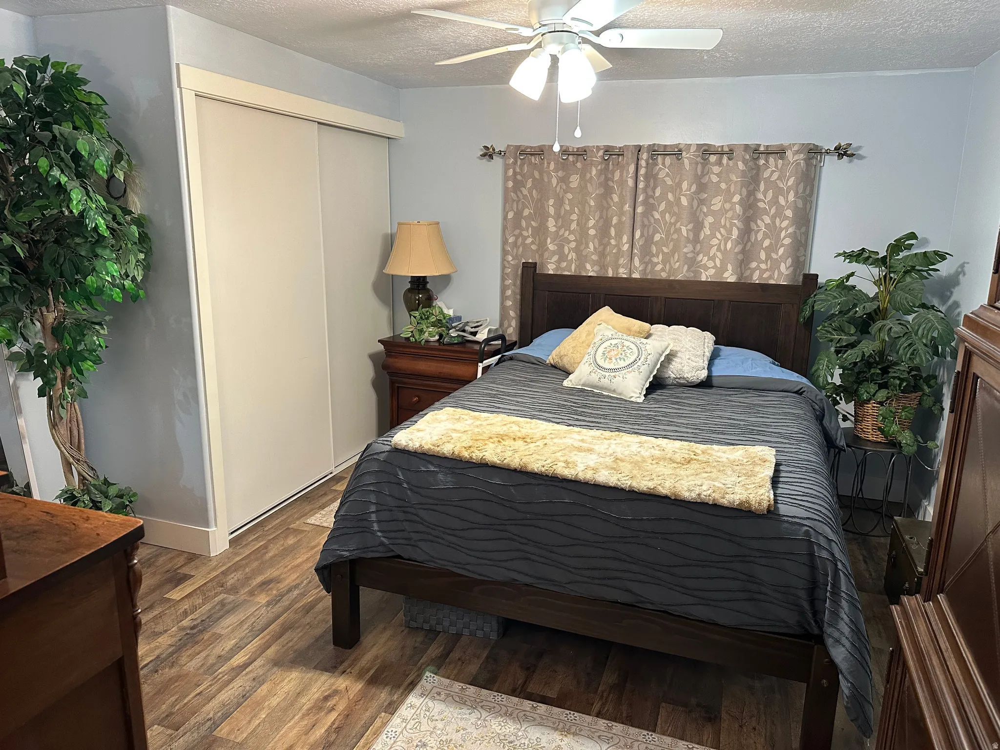 Bedroom with a textured ceiling, wood finished floors, ceiling fan, and a closet