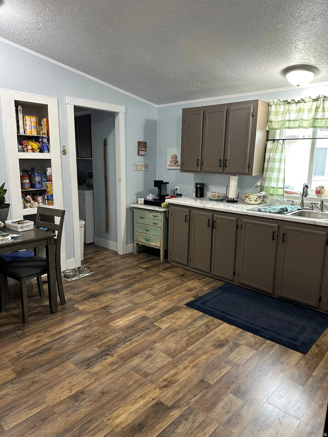 Kitchen featuring a textured ceiling, crown molding, light countertops, dark wood-style flooring, and built in features