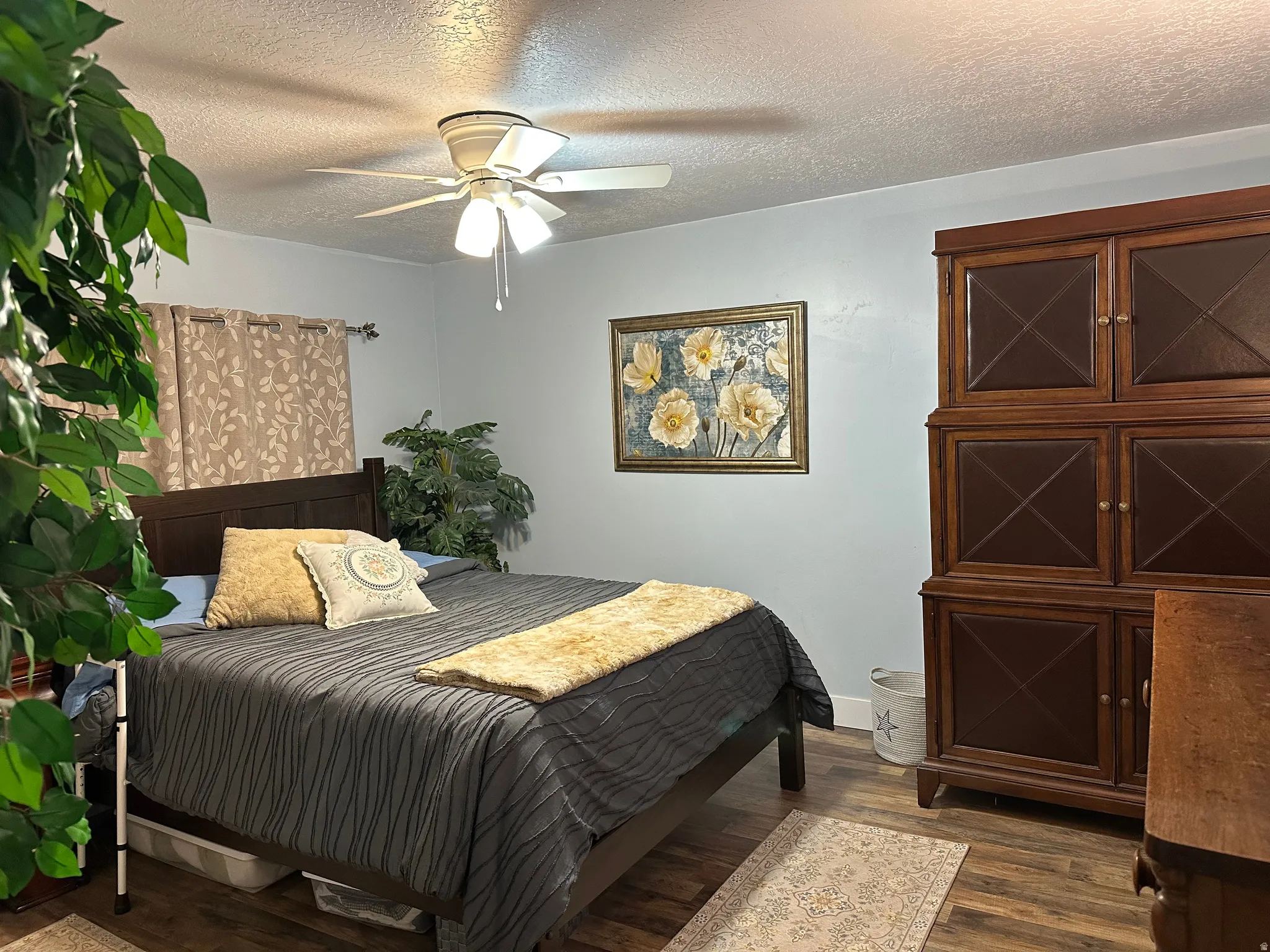 Bedroom featuring a textured ceiling, dark wood finished floors, and a ceiling fan