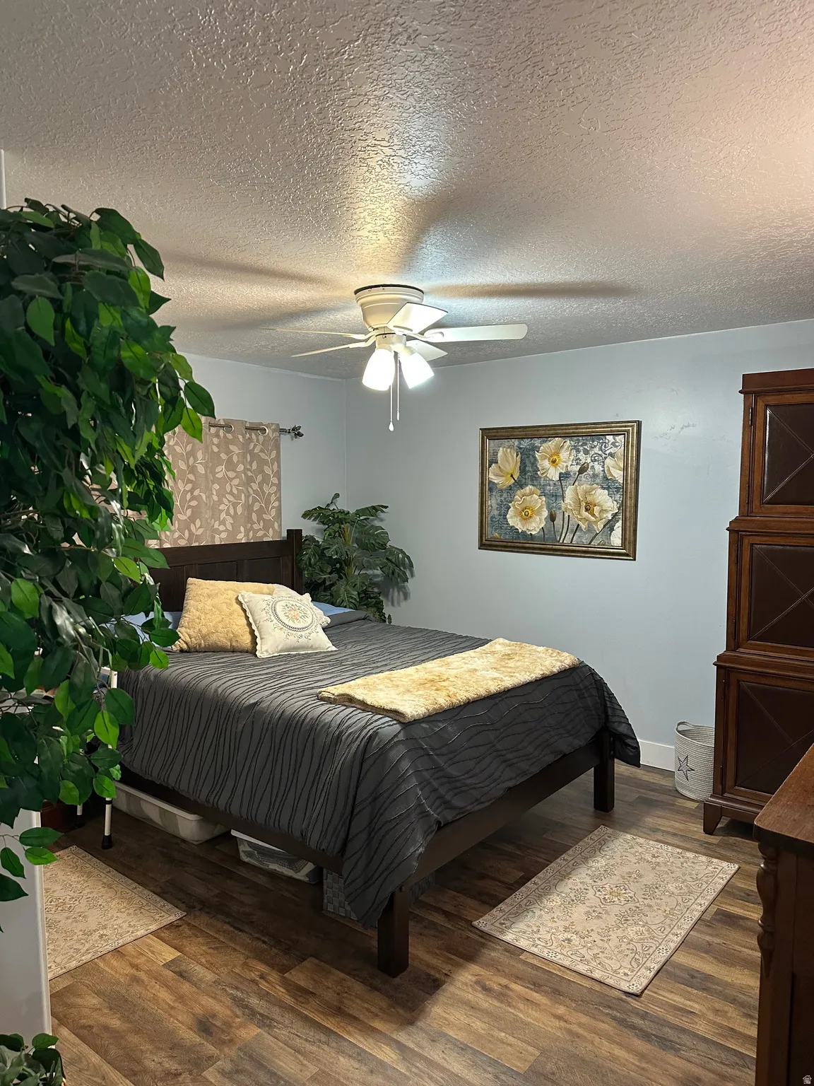 Bedroom with a textured ceiling, dark wood-style flooring, and ceiling fan