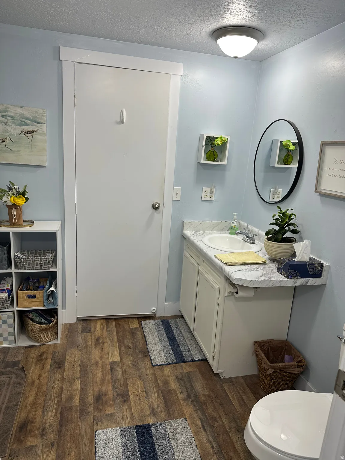 Bathroom with a textured ceiling, vanity, and dark wood-style flooring