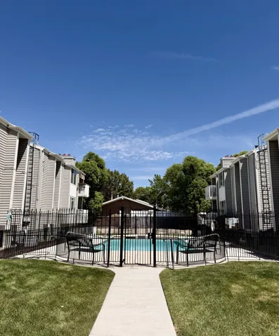 Outdoor swimming pool surrounded by black metal fencing and an adjacent lawn area
