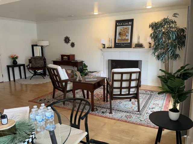 Living room featuring wood finished floors, a tiled fireplace, and crown molding