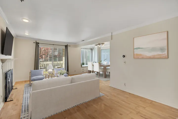 Living room featuring light wood-type flooring, ornamental molding, and a fireplace