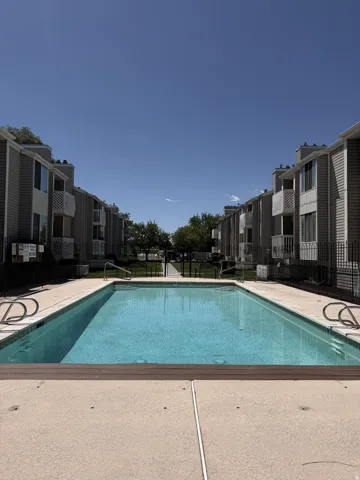 Community swimming pool featuring a concrete deck and surrounding residential buildings