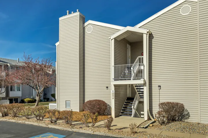 View of home's exterior with a chimney, stairs, and a balcony