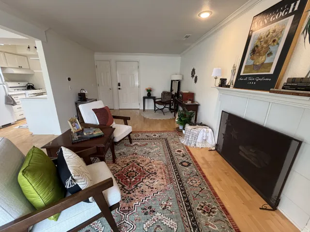 Living room featuring light wood finished floors, a tile fireplace, and ornamental molding
