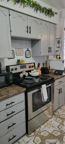Kitchen featuring stainless steel electric stove, black microwave, counters, and light floors