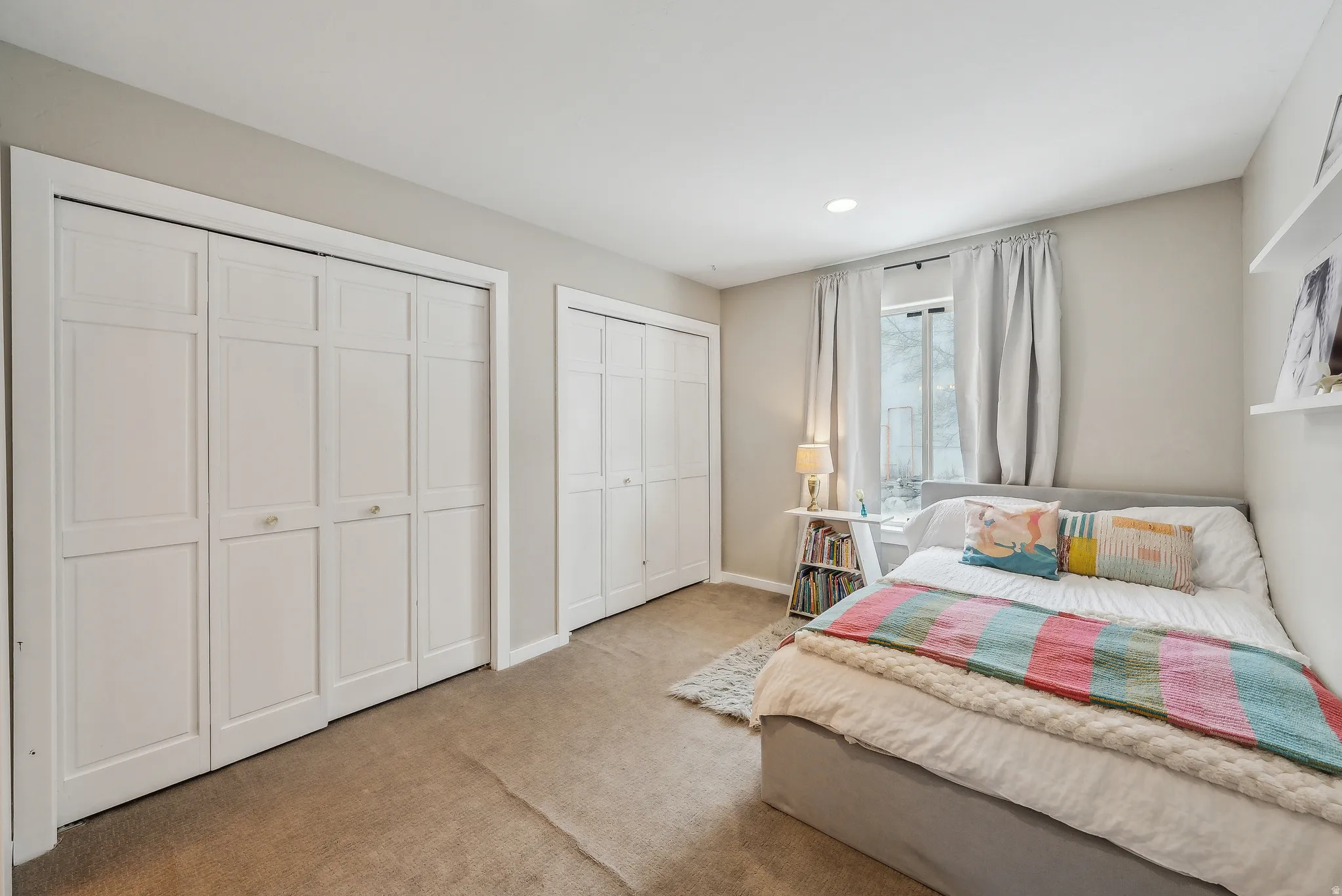 Recessed ceiling lighting, two sets of bi-fold closet doors, wall-mounted shelving, and carpeted flooring