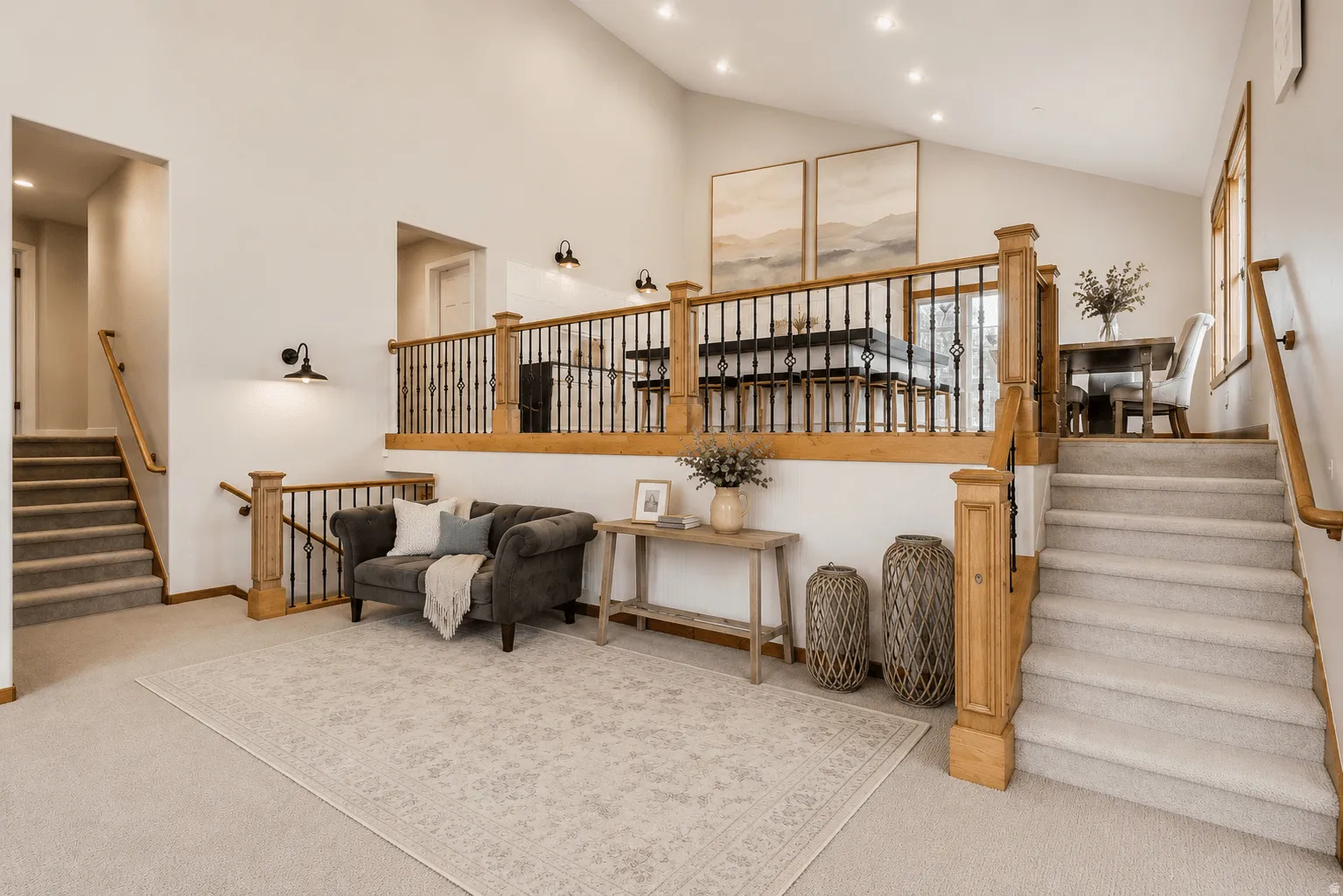 Vaulted ceilings, a carpeted staircase with wood handrails, and a second-story open railing with black spindles