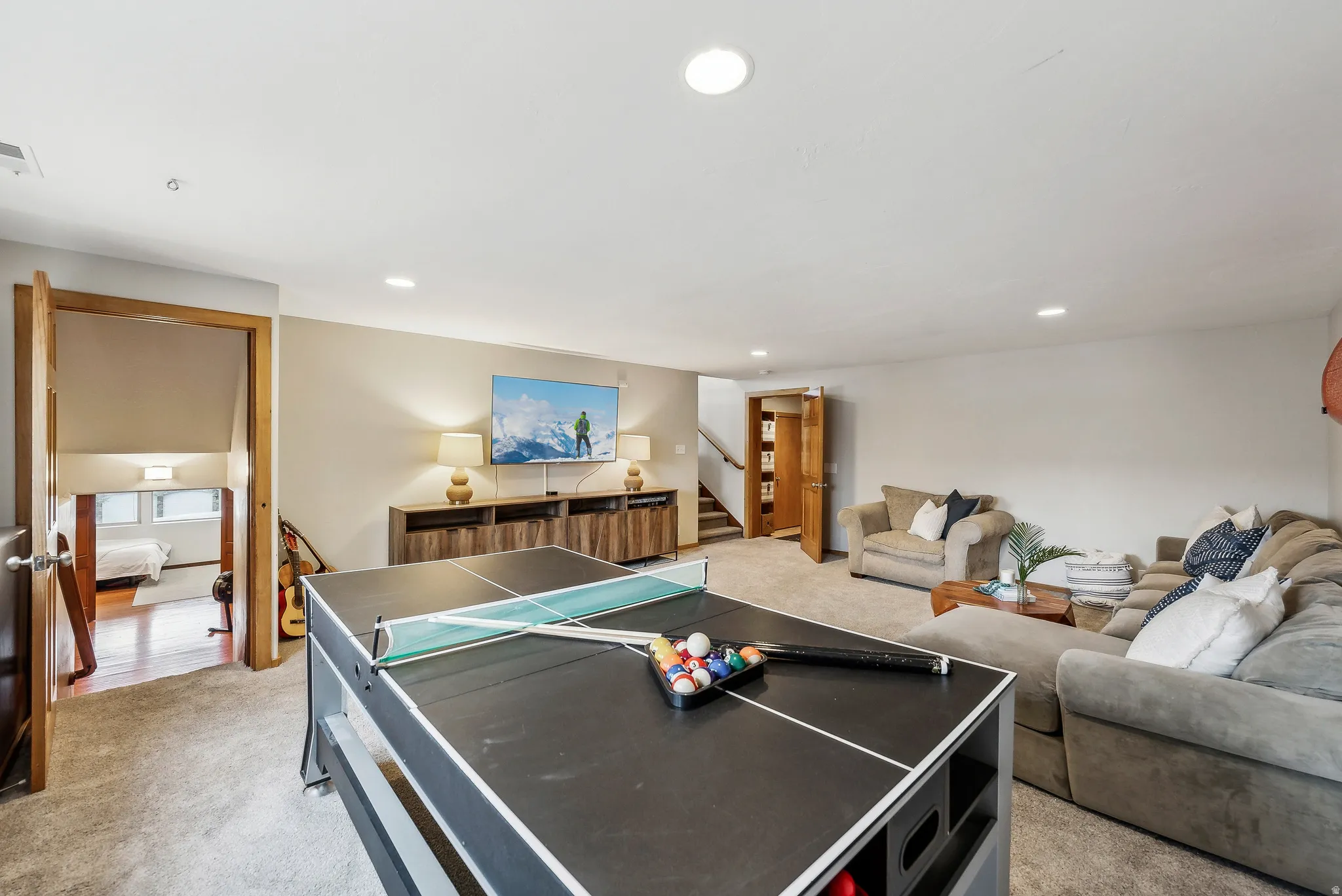 Spacious recreation room featuring carpet flooring, recessed lighting, and a wood-finish media console
