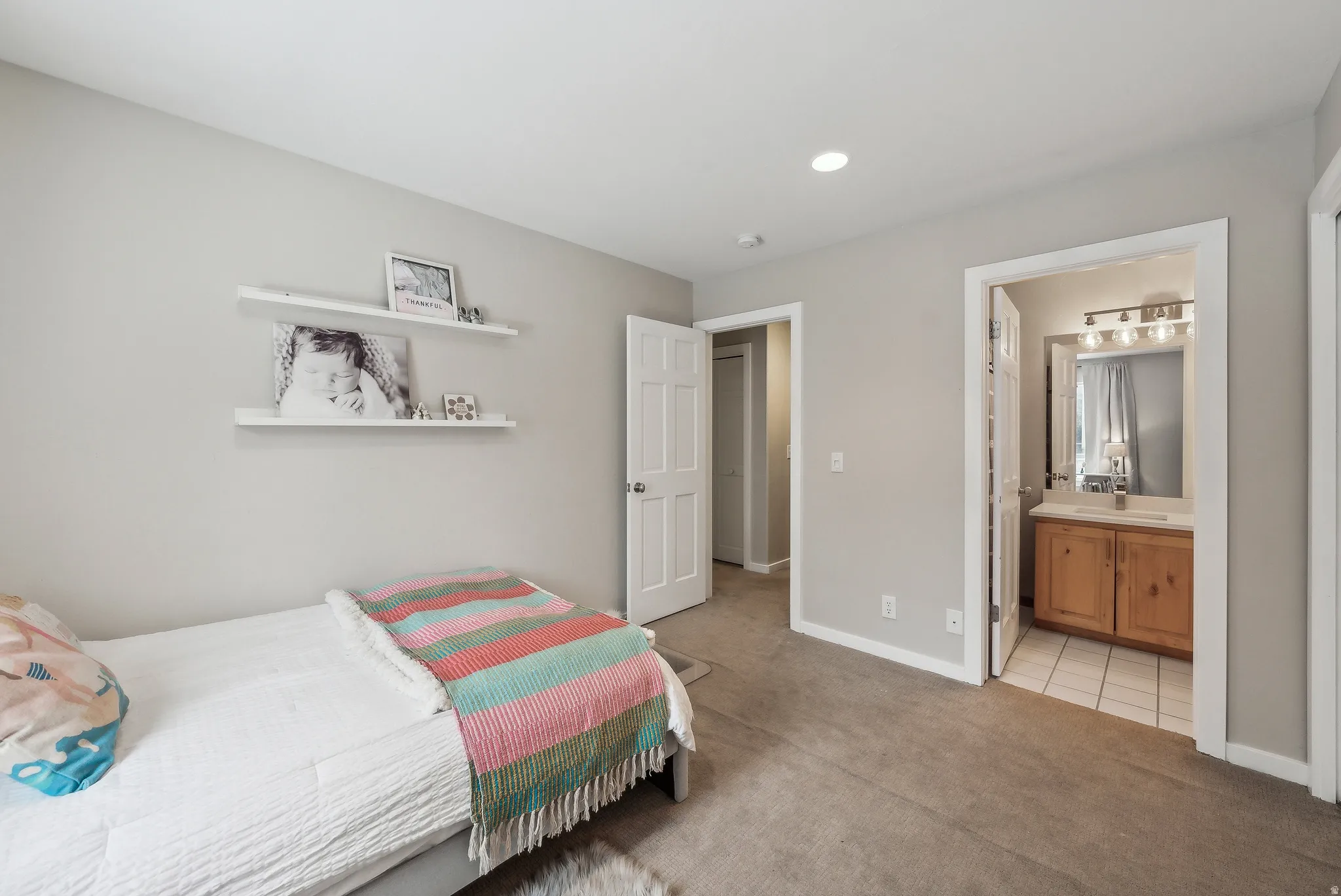 Recessed ceiling lighting, light gray wall paint, white trim, wood-finish vanity with a white countertop, and tile flooring in the bathroom