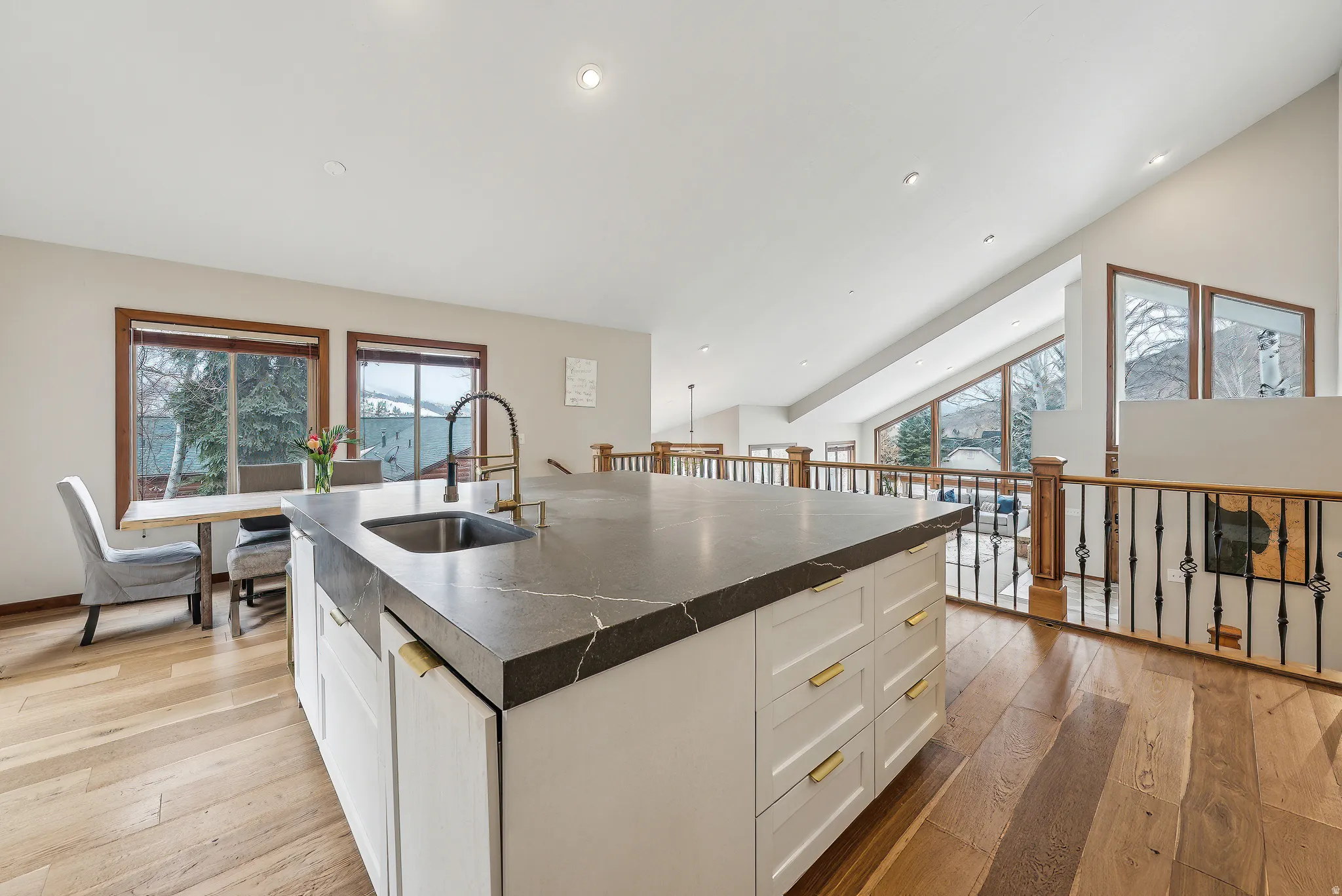 Kitchen with white cabinets, dark countertops, a kitchen island with sink, lofted ceiling, and recessed lighting