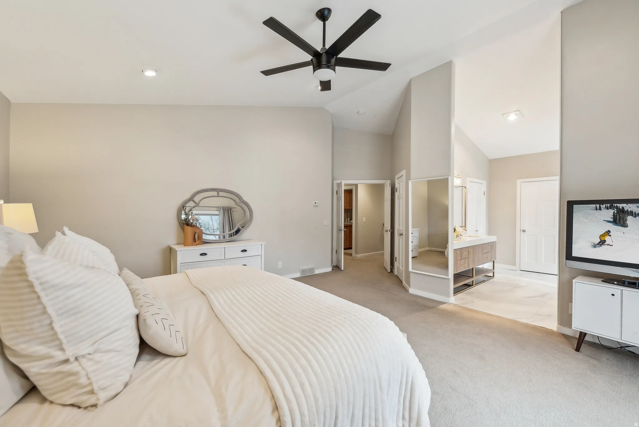 Vaulted ceilings with a ceiling fan, recessed lighting, carpeted flooring, and an integrated vanity with a mirror
