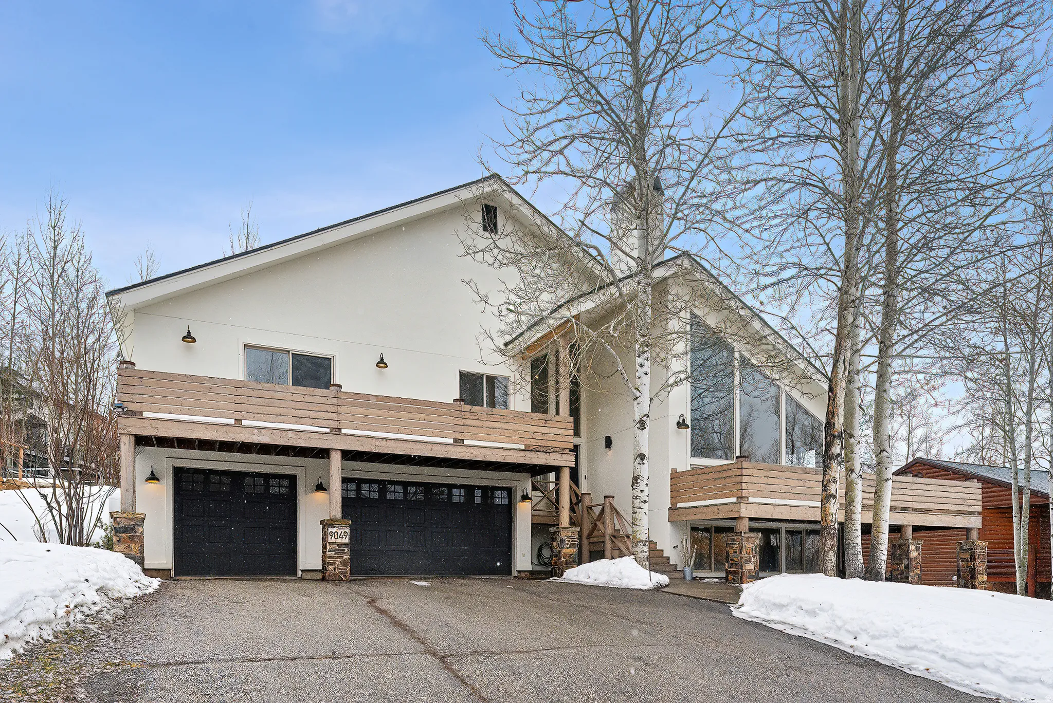 View of front facade featuring stucco siding, an attached garage, asphalt driveway, and stone siding