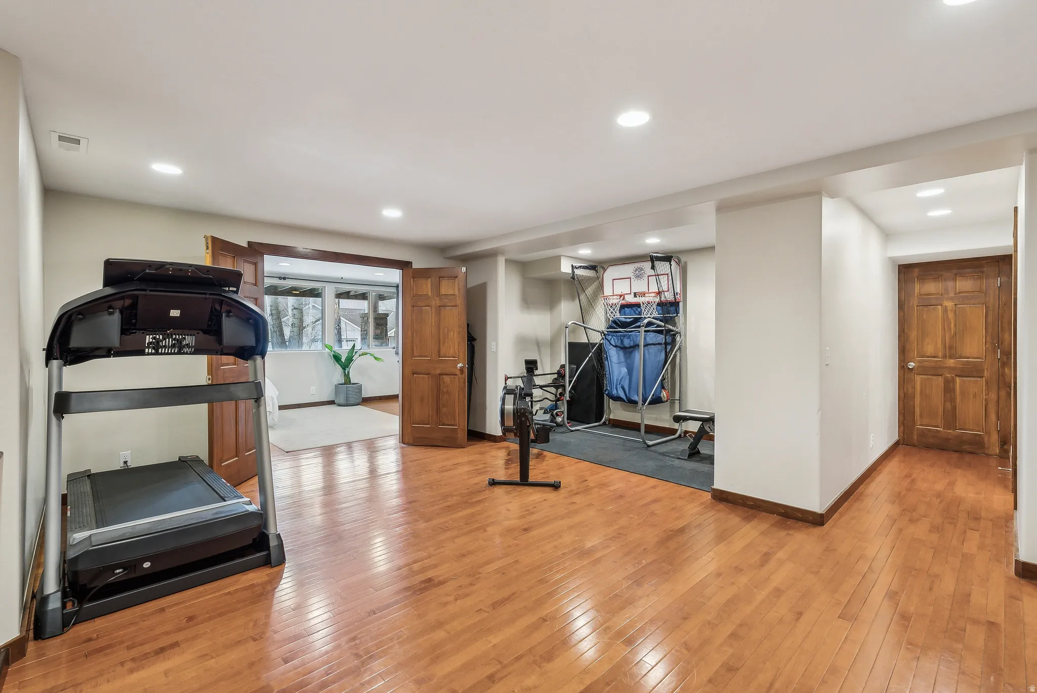 Wood-finish flooring, recessed lighting, and warm wood doors