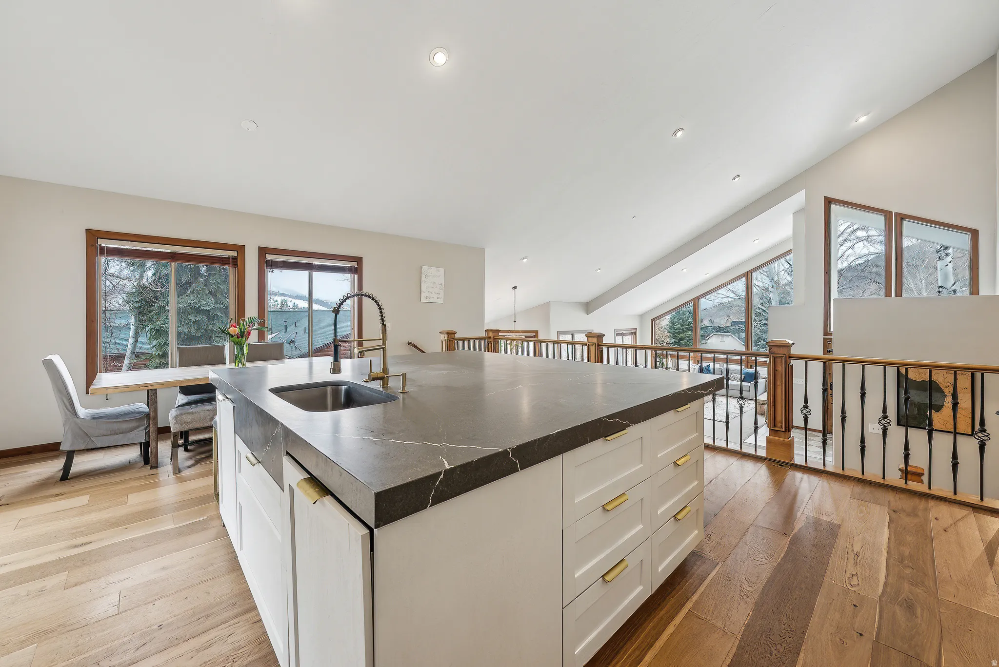 Kitchen island with integrated sink and dark countertop, complemented by white cabinetry and brass hardware