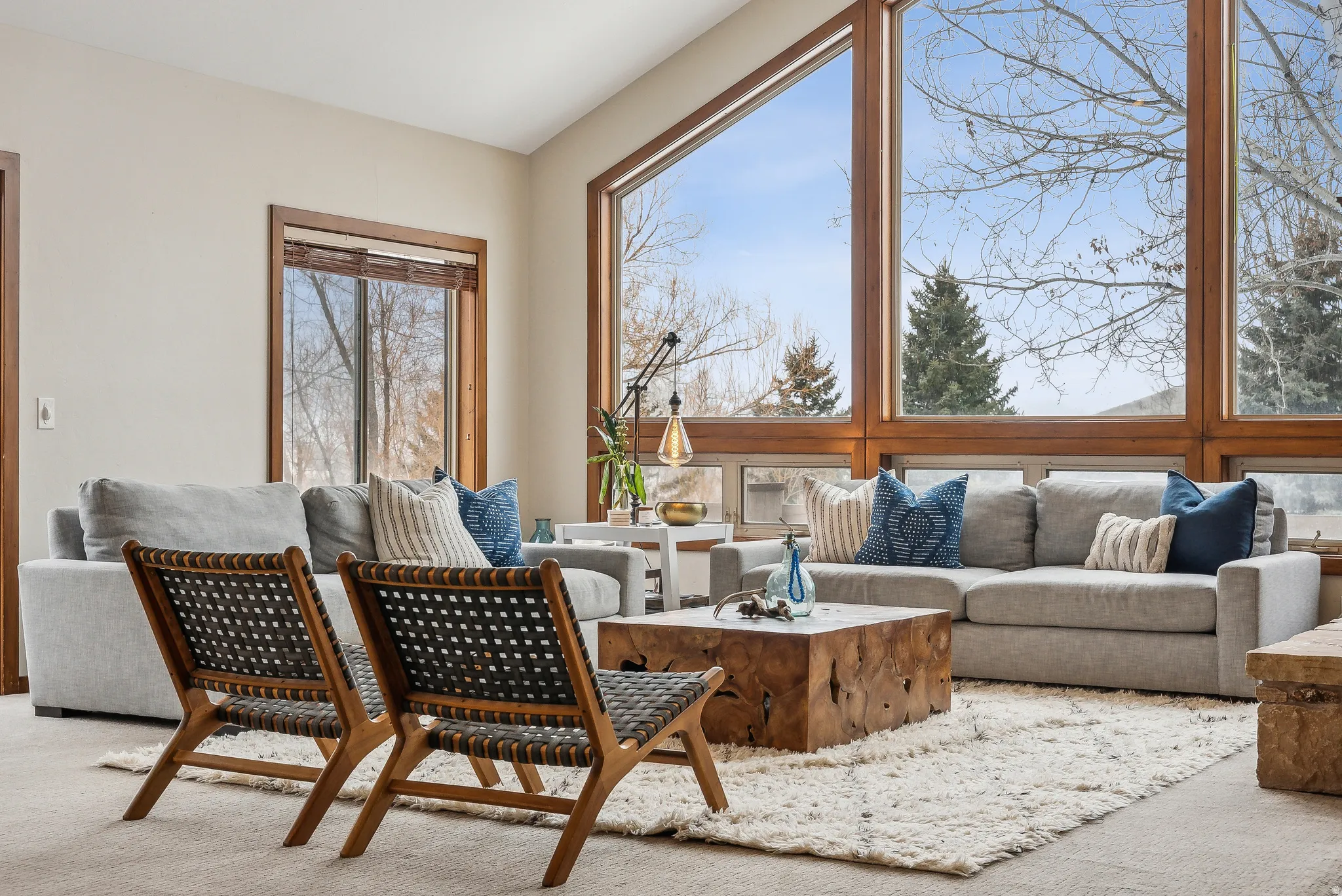 Vaulted ceiling great room with expansive wood-framed windows, natural wood window trim, and neutral wall paint