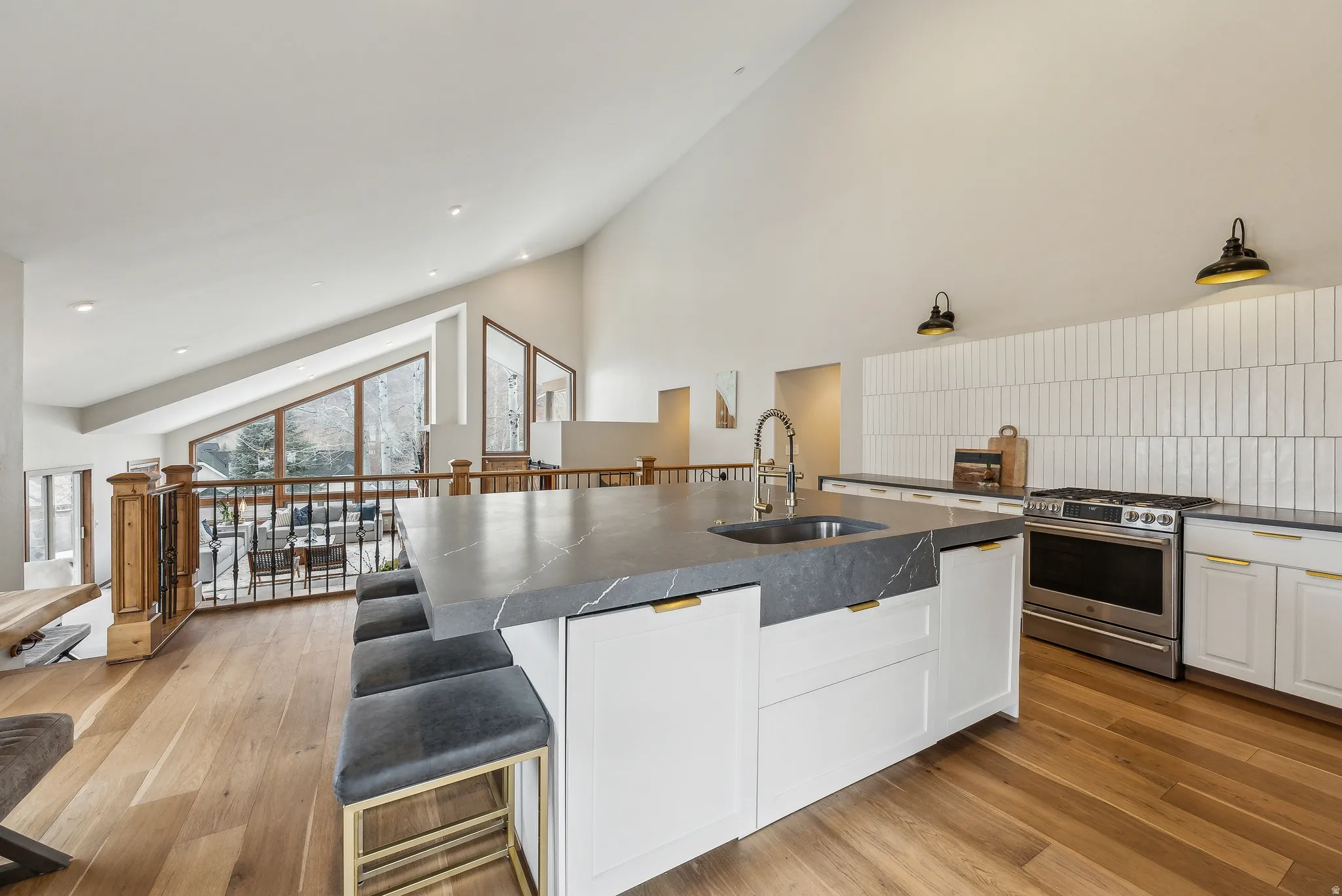 Kitchen island with an undermount sink, a stainless steel gas range, and white cabinetry
