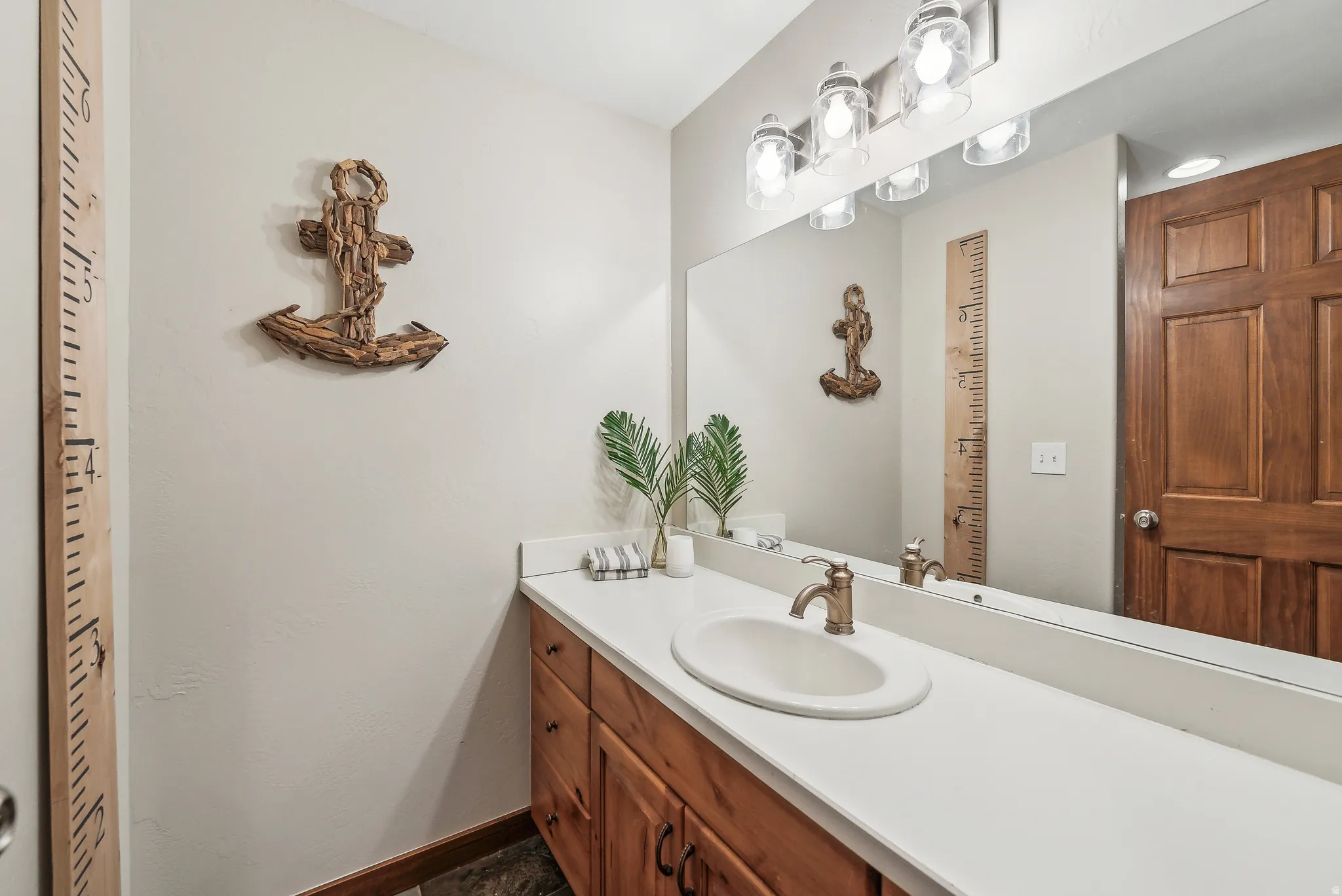Warm wood-finish cabinetry supporting a white countertop with an integrated oval sink
