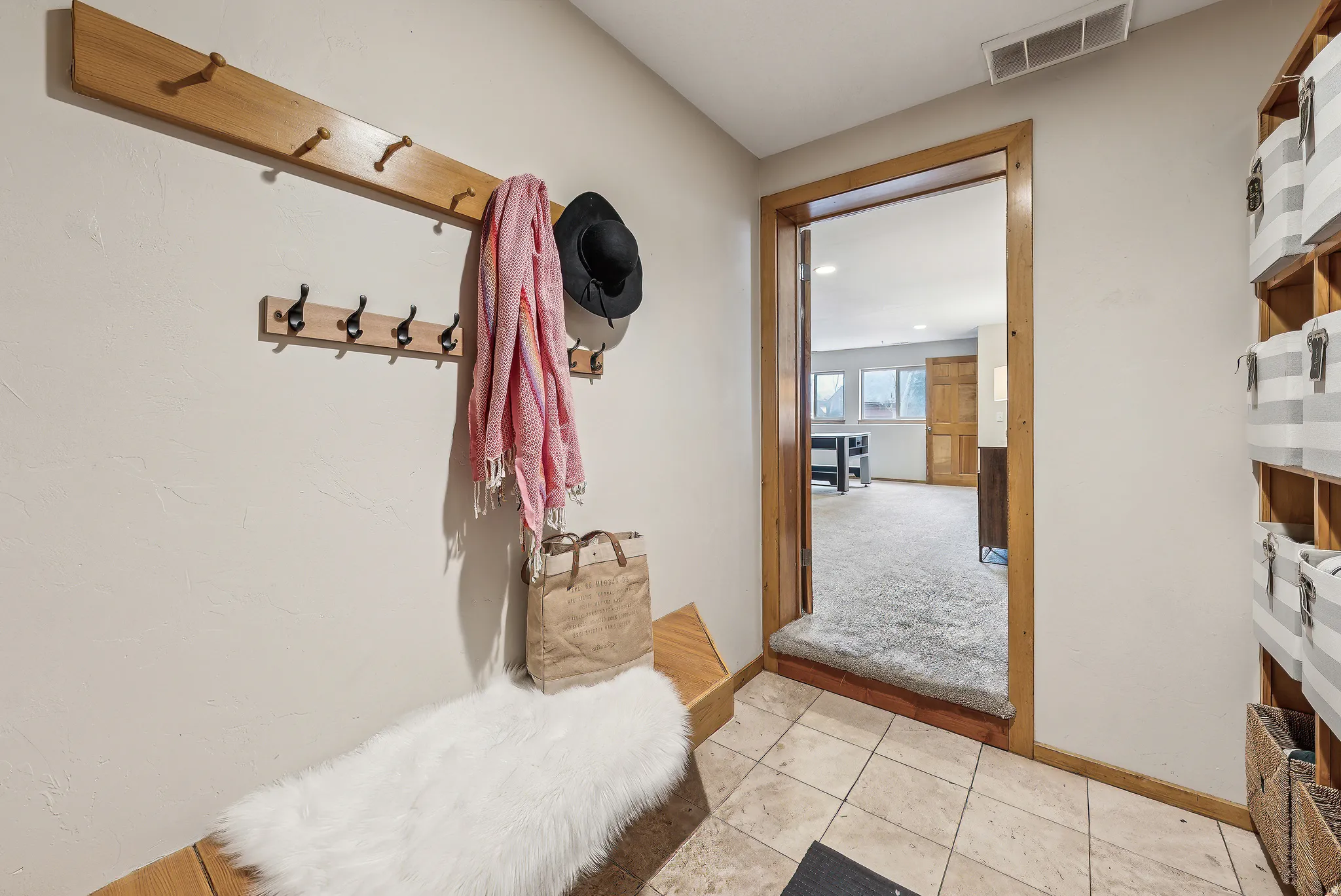Built-in wooden coat rack with multiple hooks, wood-finish trim, and tiled flooring
