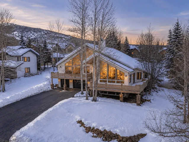 Modern A-frame architecture featuring extensive glass windows and a prominent balcony