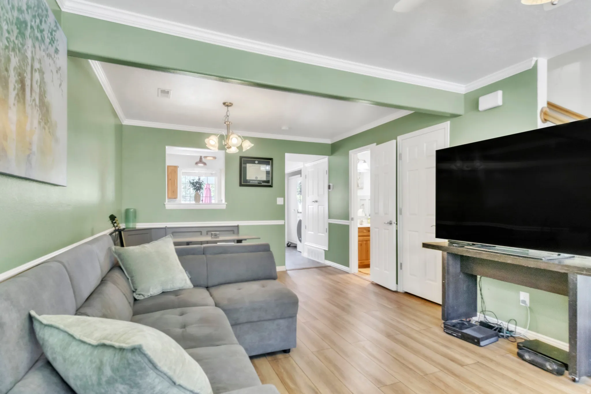Living area featuring wood finished floors, a chandelier, and ornamental molding