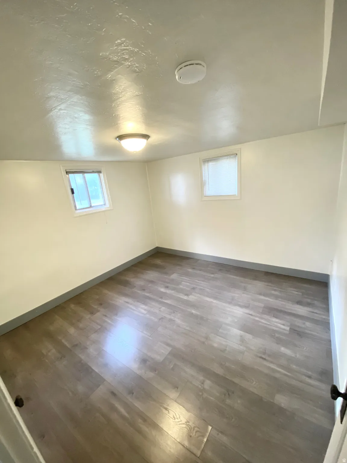 Below grade area with wood finished floors and a textured ceiling