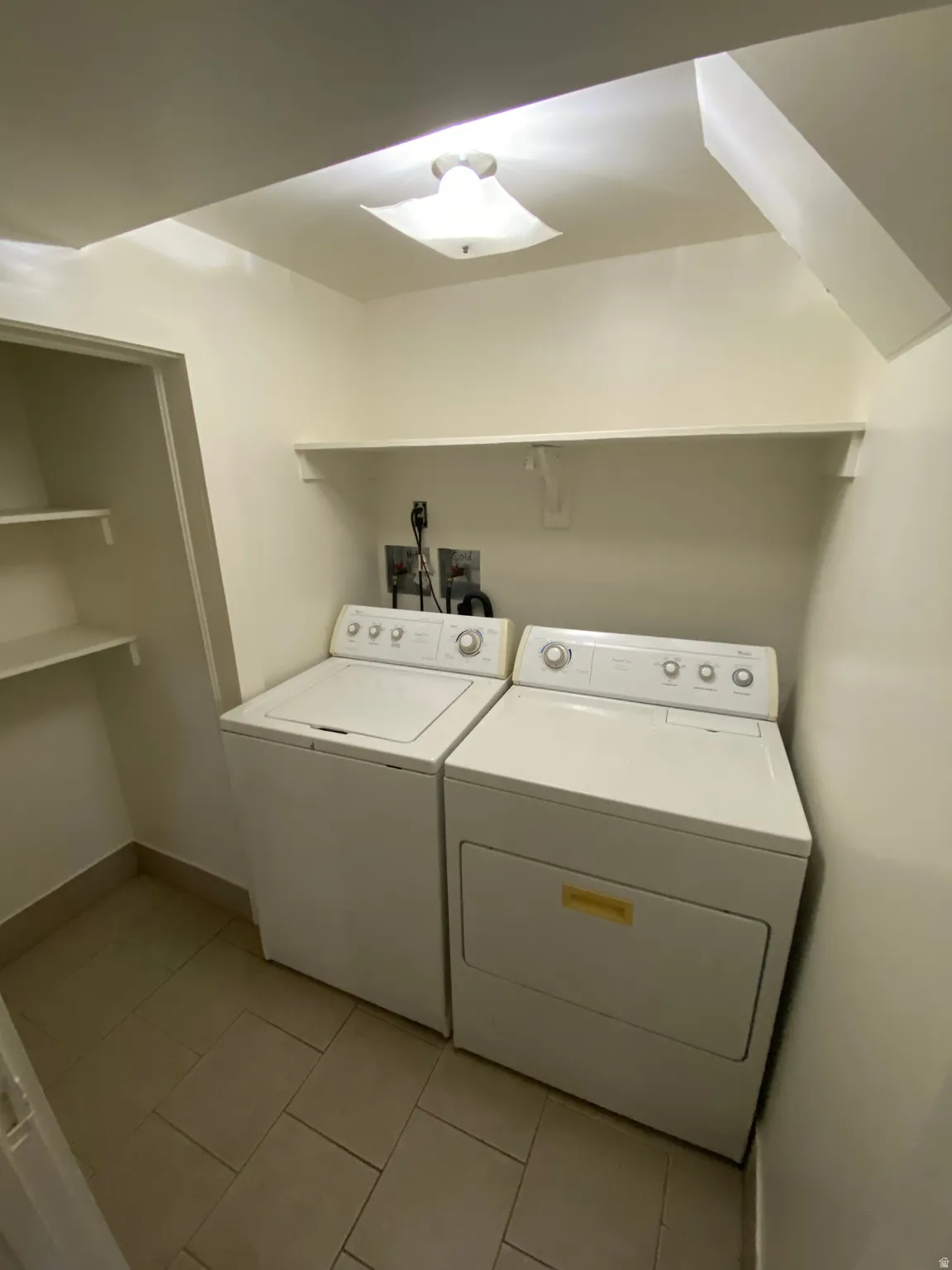Laundry room with washing machine and clothes dryer and light tile patterned flooring
